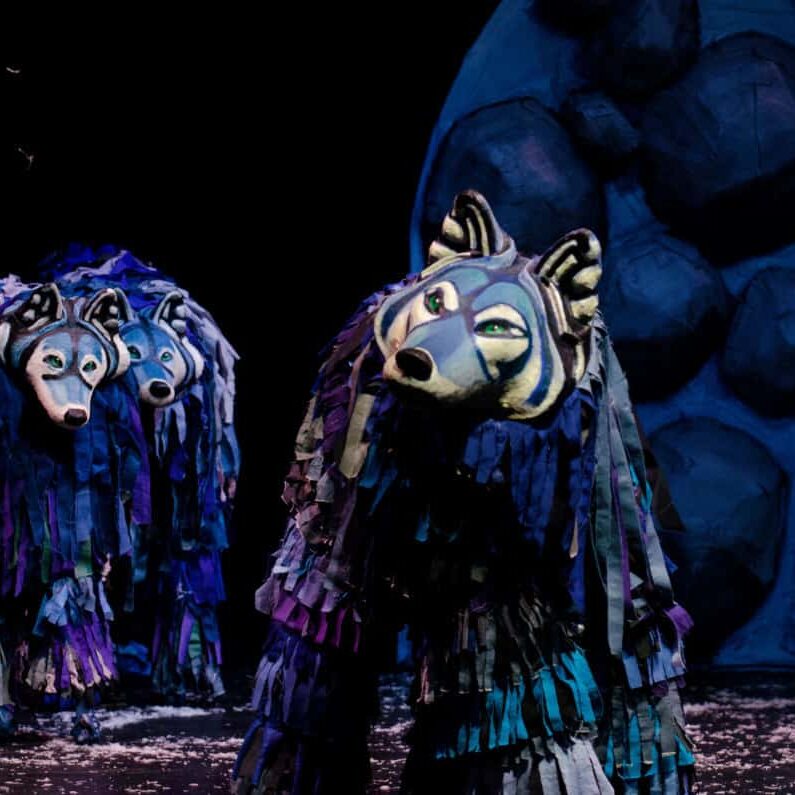 Image Description: Large wolf puppets stand on a stage.
