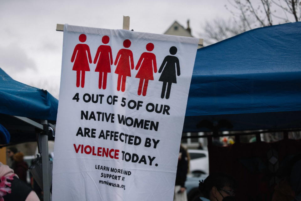 Image Description: A photo of one of MIGIZI's signs with text that reads "4 out of 5 of our Native Women are Affected By Violence Today," with 4 symbols of women in red and one in black.